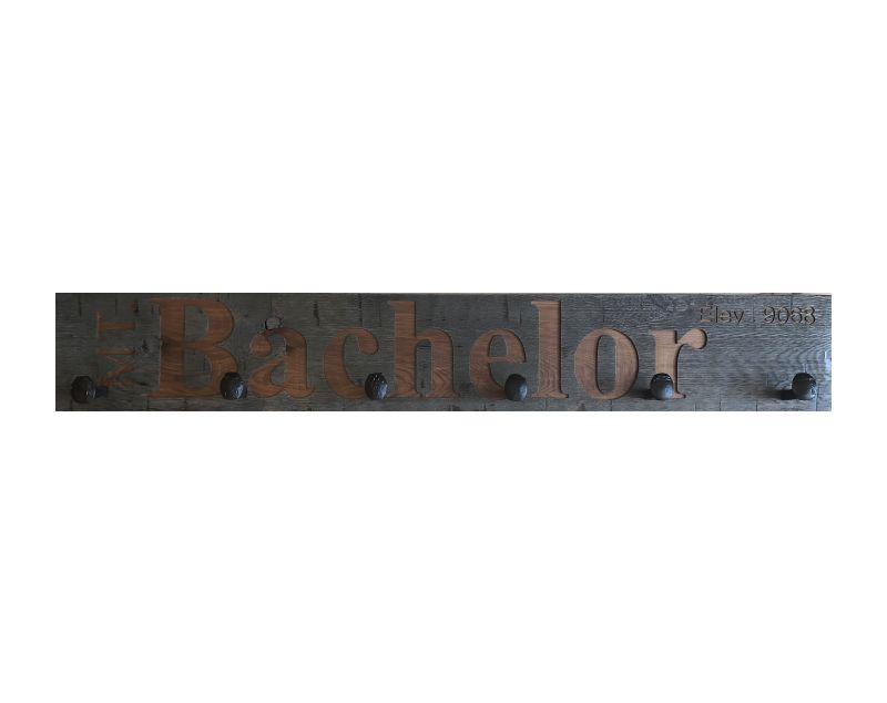 Wood wall coat rack with the words Mt, Bachelor in burned letters. Reclaimed wood and railroad spikes as hooks.