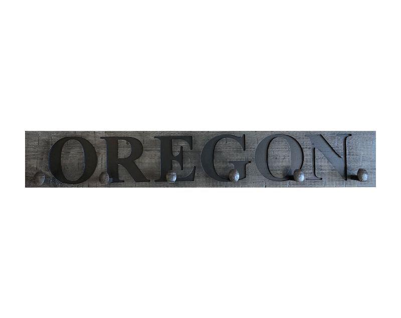 Wood wall coat rack with the words Oregon, in burned letters. Reclaimed wood and railroad spikes as hooks.