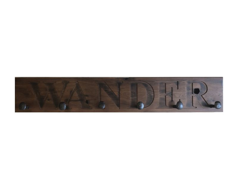 Wood wall coat rack with the words Wander, in burned letters. Reclaimed wood and railroad spikes as hooks.